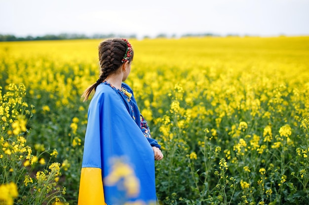 Módlcie się za Ukrainę Dziecko z ukraińską flagą na polu rzepaku Dziewczynka trzymająca w ręku flagę narodową Szczęśliwe dziecko świętujące Dzień Niepodległości