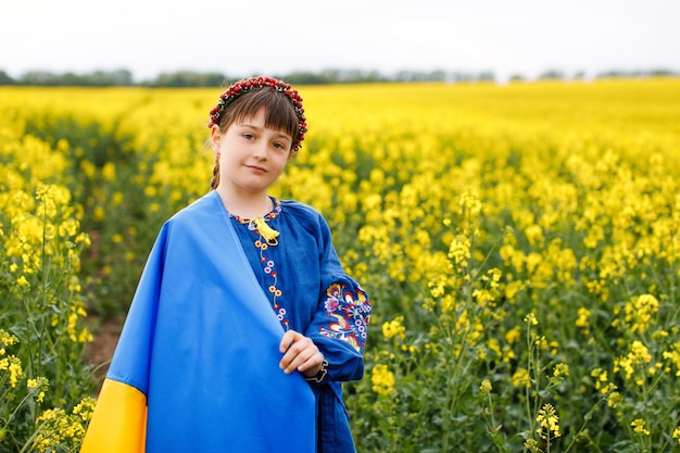 Zdjęcie módlcie się za ukrainę dziecko z ukraińską flagą na polu rzepaku dziewczynka trzymająca w ręku flagę narodową szczęśliwe dziecko świętujące dzień niepodległości