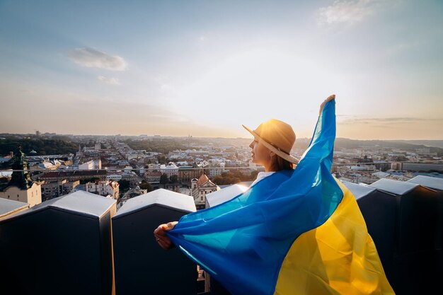 Módlcie się za UkrainexAA kobieta stoi z narodową flagą Ukrainy i macha nią modląc się o pokój o zachodzie słońca we LwowiexAA symbol niepodległości i siły narodu ukraińskiego