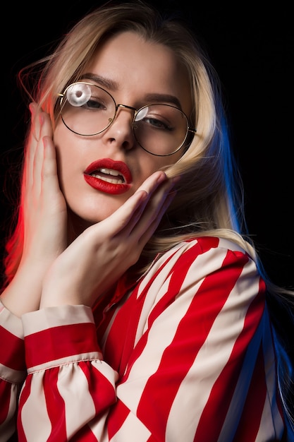 modna blond modelka pozuje z czerwonym i niebieskim światłem w studio