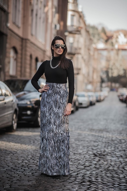 Zdjęcie modna kobieta stojąca na chodniku w mieście