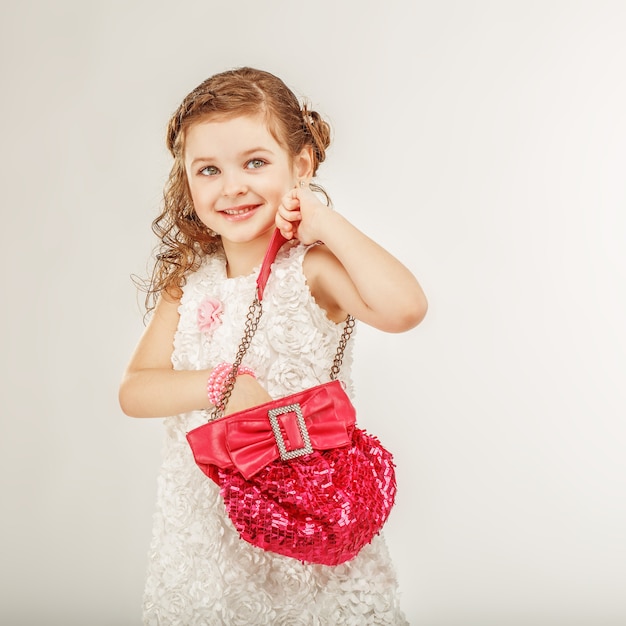 Modna mała dziewczynka trzyma różową torebkę