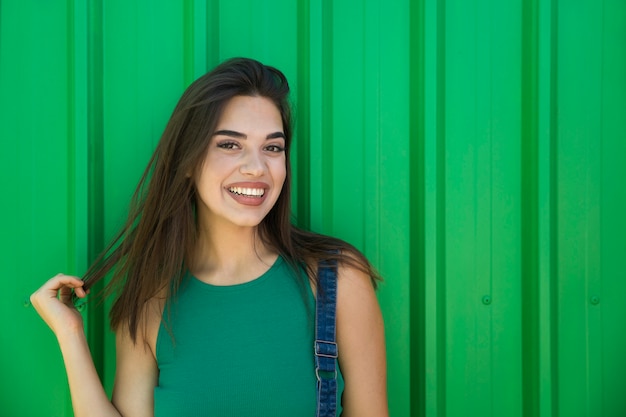 Modna młoda kobieta stojąca przy zielonej ścianie
