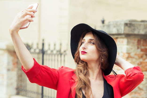 Modna piękna dorosła dziewczyna bierze selfie na zewnątrz.