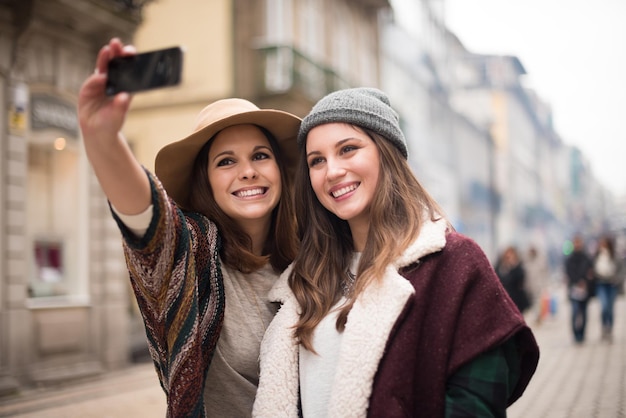 Modne młode kobiety robiące selfie w mieście