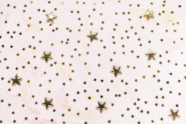 Zdjęcie modne złote konfetti foliowe gwiazdki na różowym tle.