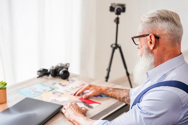 Modny Fotograf W Swoim Kreatywnym Studiu, Wybierając Zdjęcia. Hipster Człowieka W Pracy