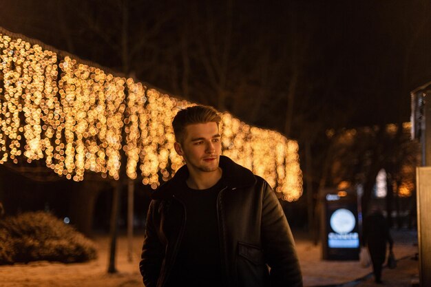 Modny Przystojny Hipster Facet Z Włosami W Modnej Skórzanej Vintage Czarnej Kurtce Z Futrem Chodzenie Po Nocnym Mieście Z żółtymi światłami Weekend świąteczny