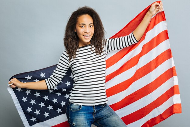 Moja flaga. Zadowolona młoda kobieta patrząc w kamerę i wyciągając ramiona, wyrażając jednocześnie pozytywne nastawienie