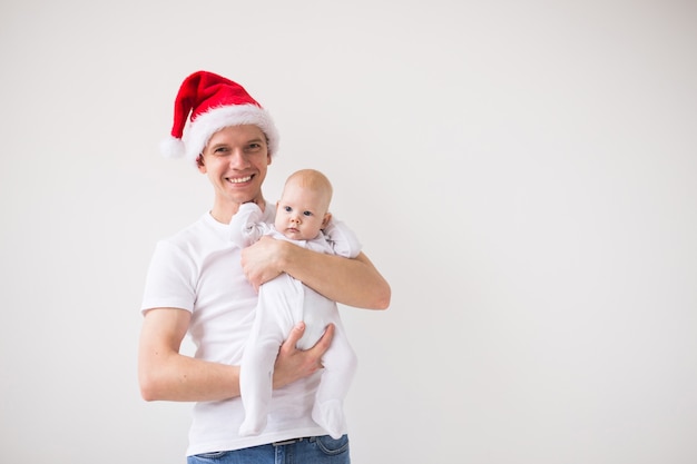 Moje pierwsze święta. Tata w santa hat trzymając córkę córeczkę na białym tle z miejsca na kopię