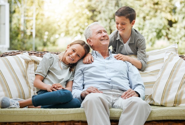 Moje wnuki są dla mnie całym światem. Ujęcie starszego mężczyzny siedzącego na zewnątrz z dwójką wnuków.