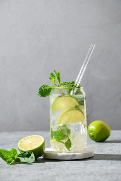 Mojito z limonkową miętą i kostką lodu na szarym tle