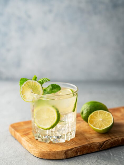 Mojito z świeżym cytrusem na drewnianej desce na niebieskim tle Odświeżający koktajl z cytrusami, miętą i lodem