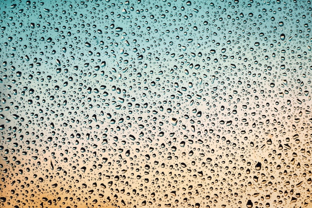 Mokre okno turkusowe pomarańczowe tło krople wody na szkle deszczowa pogoda kopia przestrzeń