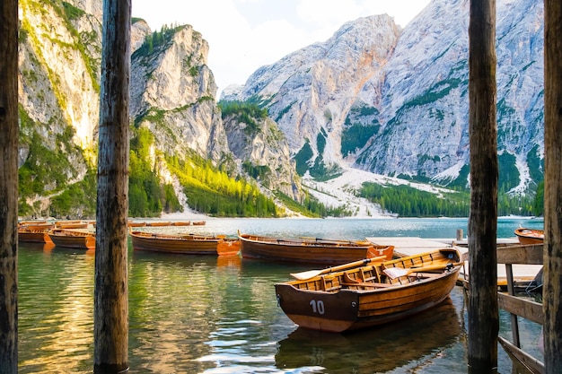 Molo z wiązanymi drewnianymi łodziami na jeziorze Braies i Alpach Dolomitów w tle