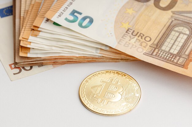 Moneta Bitcoin i banknoty euro. Blockchain a koncepcja pieniądza fiducjarnego