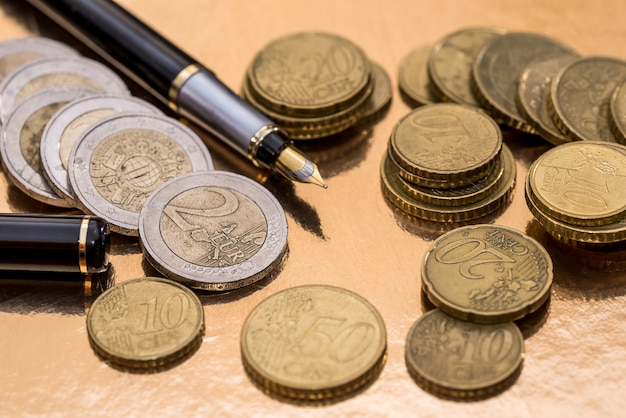 Monety euro i pióra na białym tle na złoto