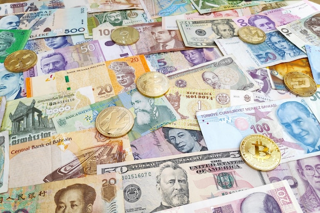 Monety kryptowalutowe na stosie międzynarodowych banknotów