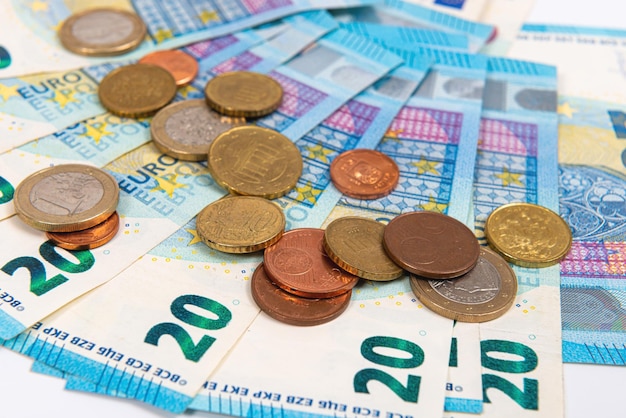 monety na tle dwudziestu banknotów euro z bliska
