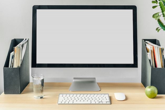 Monitor komputerowy z białym ekranem makiety na stole biurowym z materiałami eksploatacyjnymi