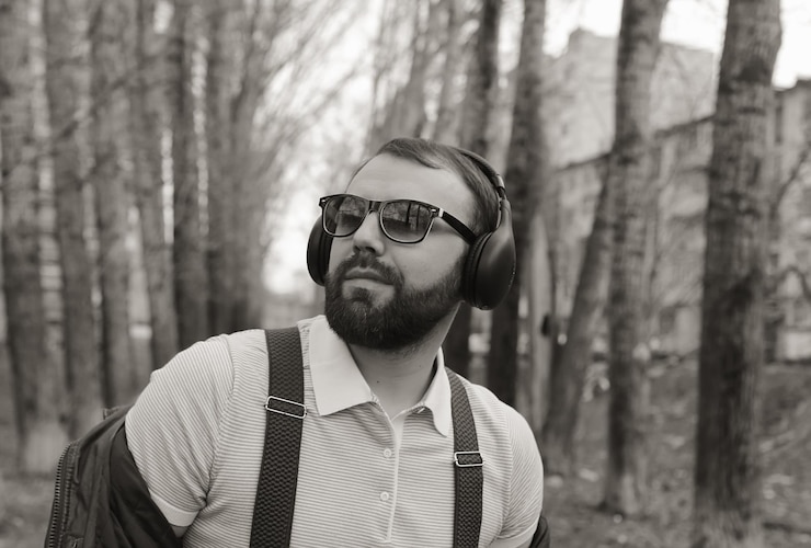 Zdjęcie monochromatyczny mężczyzna z brodą słucha muzyki w parku
