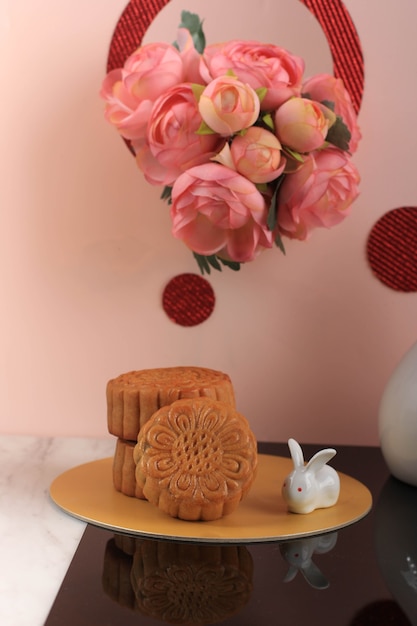 Mooncake na jasnoróżowym tle z różowym kwiatem. Koncepcja Moon Cake na Święto Środka Jesieni. Mooncake Popularny jako Kue Bulan.