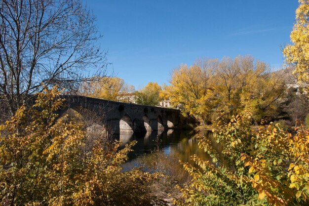 Most łukowy nad rzeką na tle nieba jesienią