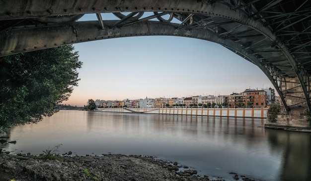 Zdjęcie most triana nad rzeką guadalquivir podczas zachodu słońca