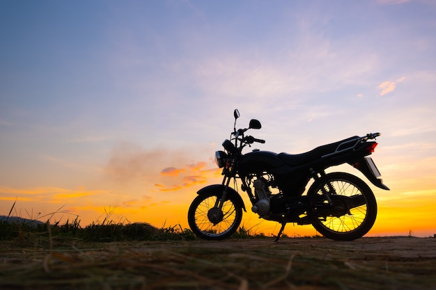Motocykl o zachodzie i wschodzie słońca z miejsca na kopię. Motocykl sylwetka.