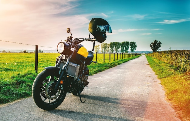 Motocykl zaparkowany na drodze przez trawiaste pole na tle nieba