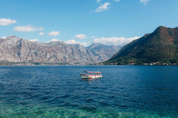 Motorówka w turkusowej zatoce kotorskiej na tle gór z widokiem na perast