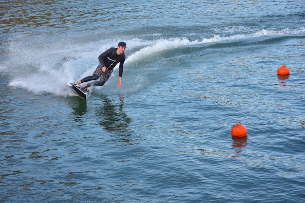 Motosurf Zawodnik szybko pokonuje zakręt i robi dużo sprayu. Jet surfing na wodzie, człowiek na desce surfingowej jet. Surfer w ruchu, letni sport