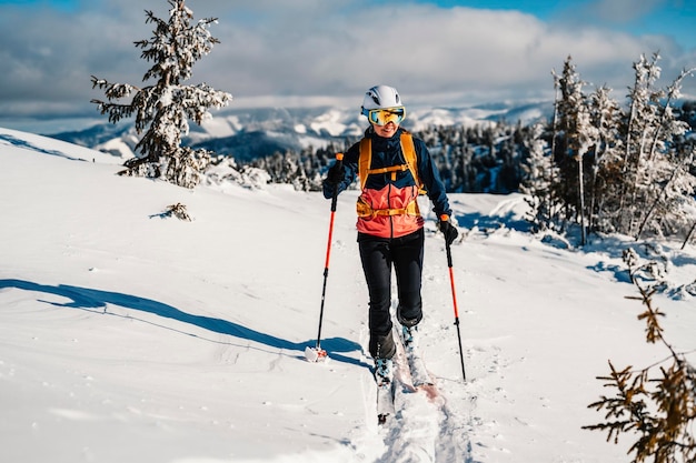 Mountaineer backcountry ski walking na nartach kobieta alpinistka w górach Skialpinizm w alpejskim krajobrazie z ośnieżonymi drzewami Przygoda sporty zimowe Freeride narty