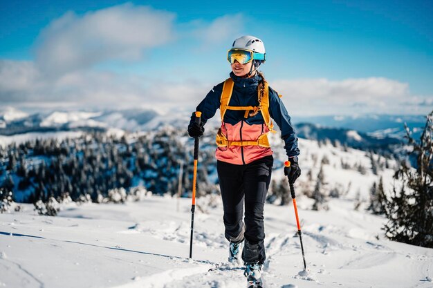 Mountaineer backcountry ski walking na nartach kobieta alpinistka w górach Skialpinizm w alpejskim krajobrazie z ośnieżonymi drzewami Przygoda sporty zimowe Freeride narty