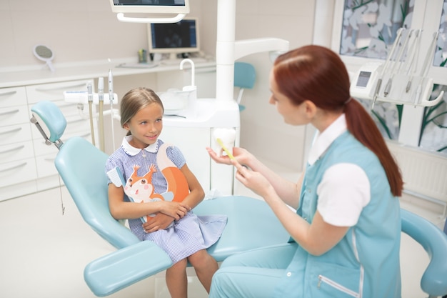 Mówiąc o zębach. Widok z góry na dziewczynę patrzącą na dentystę opowiadającą o zębach i opiece stomatologicznej