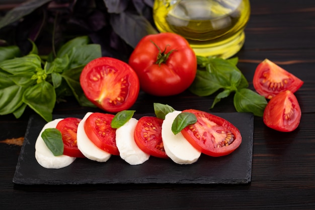 Zdjęcie mozzarella, bazylia i pomidor na łupkowej kamiennej desce, kopii przestrzeń.