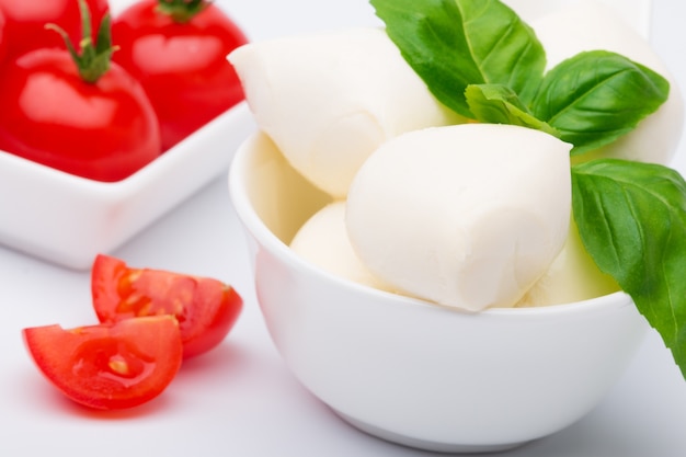 Mozzarella, świeże pomidory i liście bazylii leżące w misce