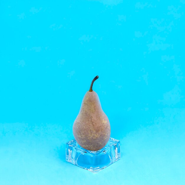 Mrożona gruszka na kostce lodu na niebieskim tle szybko mrożone owoce zachowują świeżość i witaminy
