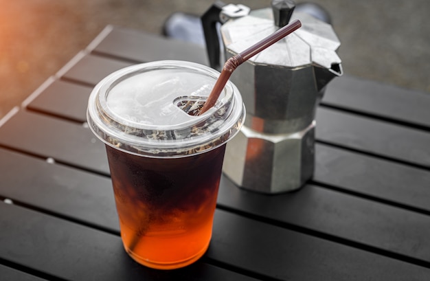 Mrożona kawa americano w plastikowym szkle z ulicznej kawiarni w stylu azjatyckim z oświetleniem zewnętrznym.