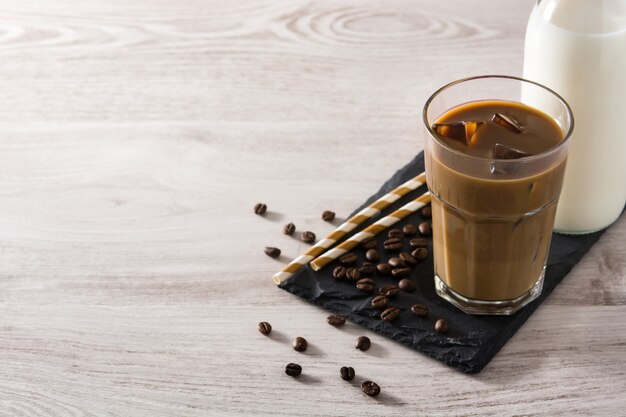 Mrożona kawa lub caffe latte w wysokiej szklance na białym stole z drewna