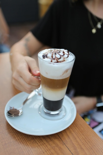 Mrożona kawa z mlekiem Mrożona kawa latte Kobieta trzymająca szklany kubek mrożonej kawy