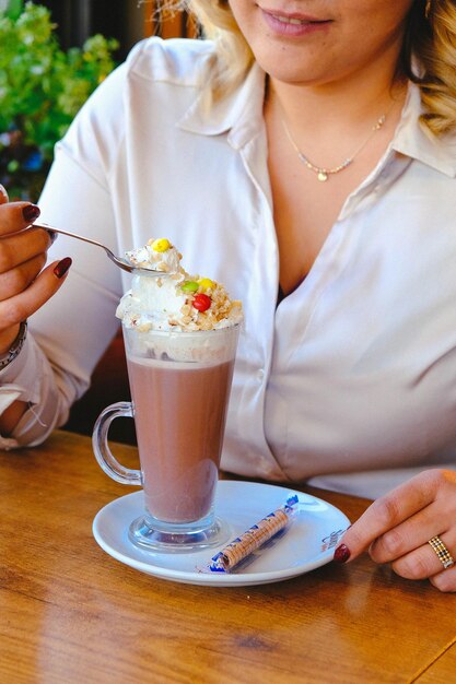 Mrożona kawa z mlekiem Mrożona kawa latte Kobieta trzymająca szklany kubek mrożonej kawy