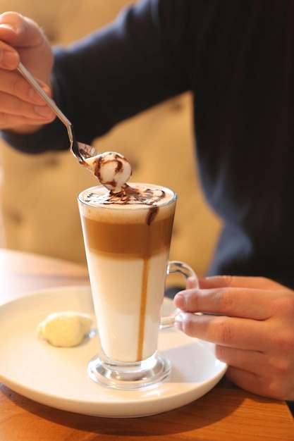 Mrożona kawa z mlekiem Mrożona kawa latte Kobieta trzymająca szklany kubek mrożonej kawy