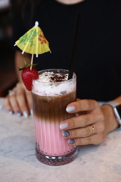 Mrożona kawa z mlekiem Mrożona kawa latte Kobieta trzymająca szklany kubek mrożonej kawy