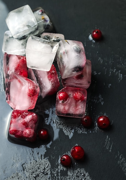 Mrożone jagody w kostkach lodu na ciemnej powierzchni