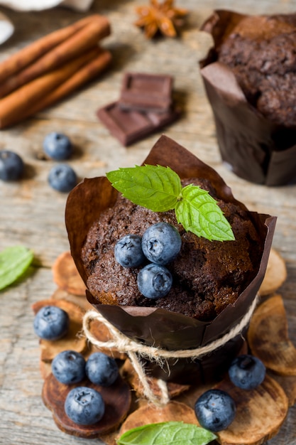 Muffin czekoladowy z miętą i jagodami na drewnianym stojaku