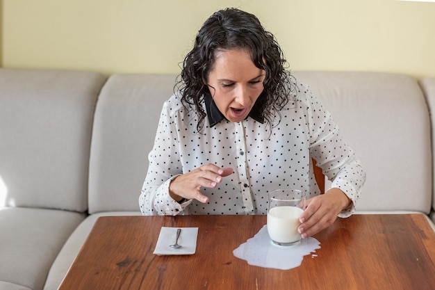 Mujer derrama un vaso de leche en la mesa