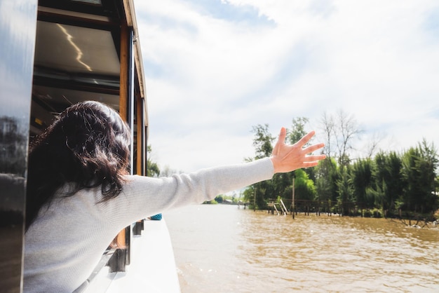 Mujer viajera con sobrero navegando en barco por el rio