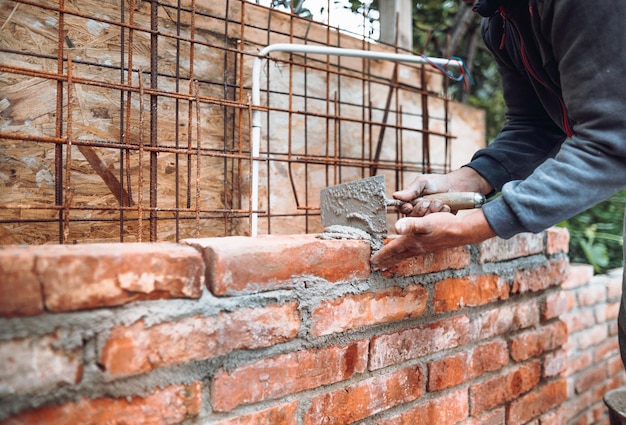 Murarz budowlany buduje ściany z cegły za pomocą zaprawy kielni Szczegóły branży
