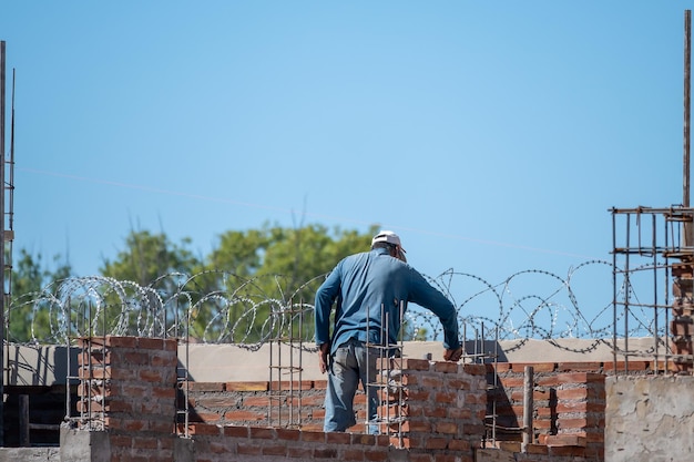 Murarz układający cegły mułowe w budowie domu w Argentynie